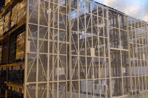 Tall pallet racking goods storage with protective cage