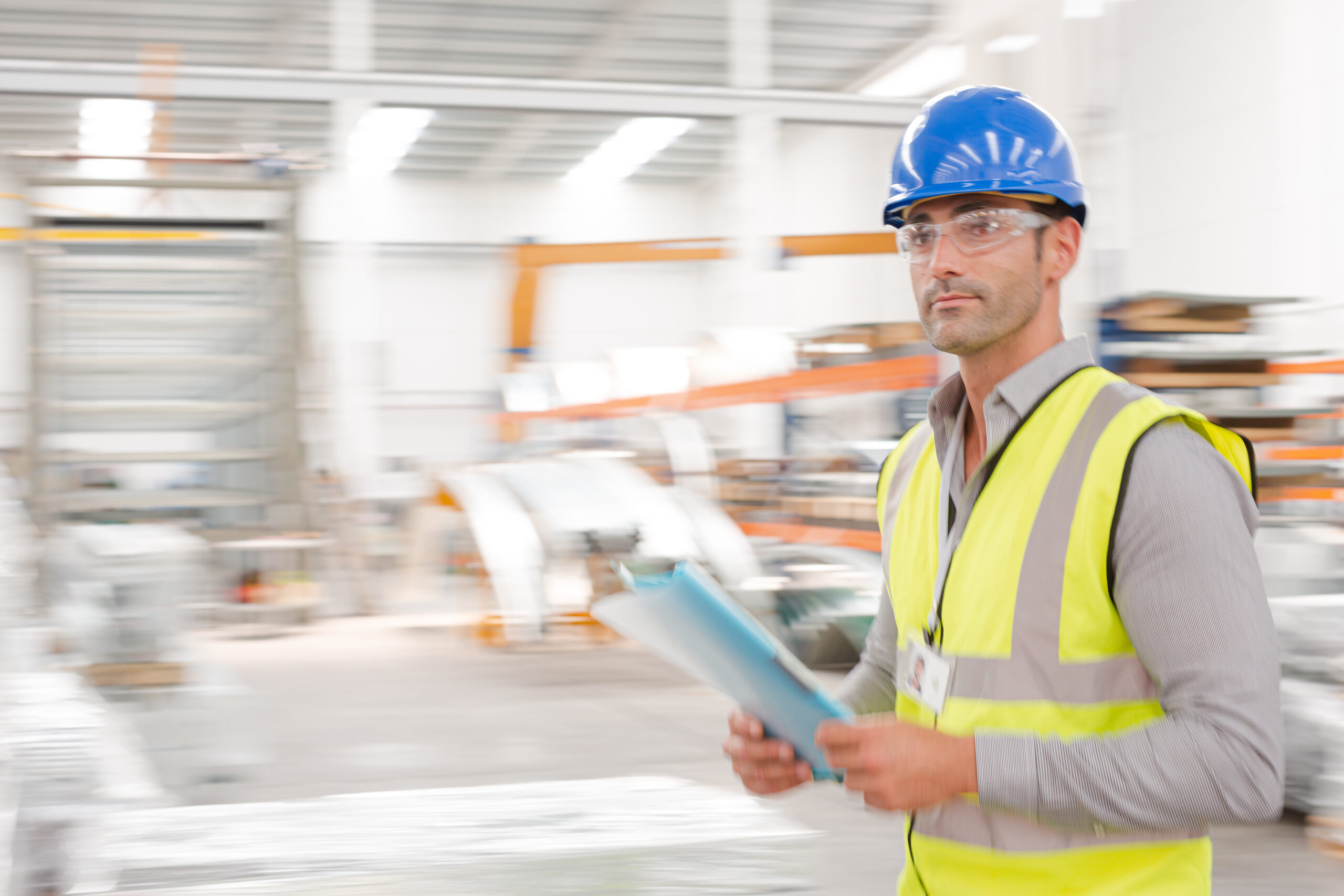 Male supervisor with paperwork walking in a warehouse