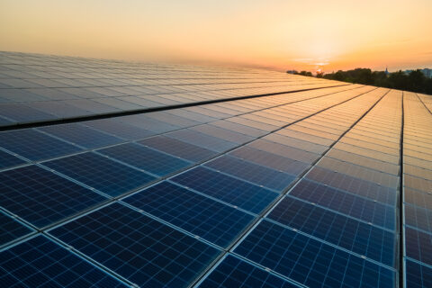 Blue photovoltaic solar panels mounted on warehouse roof