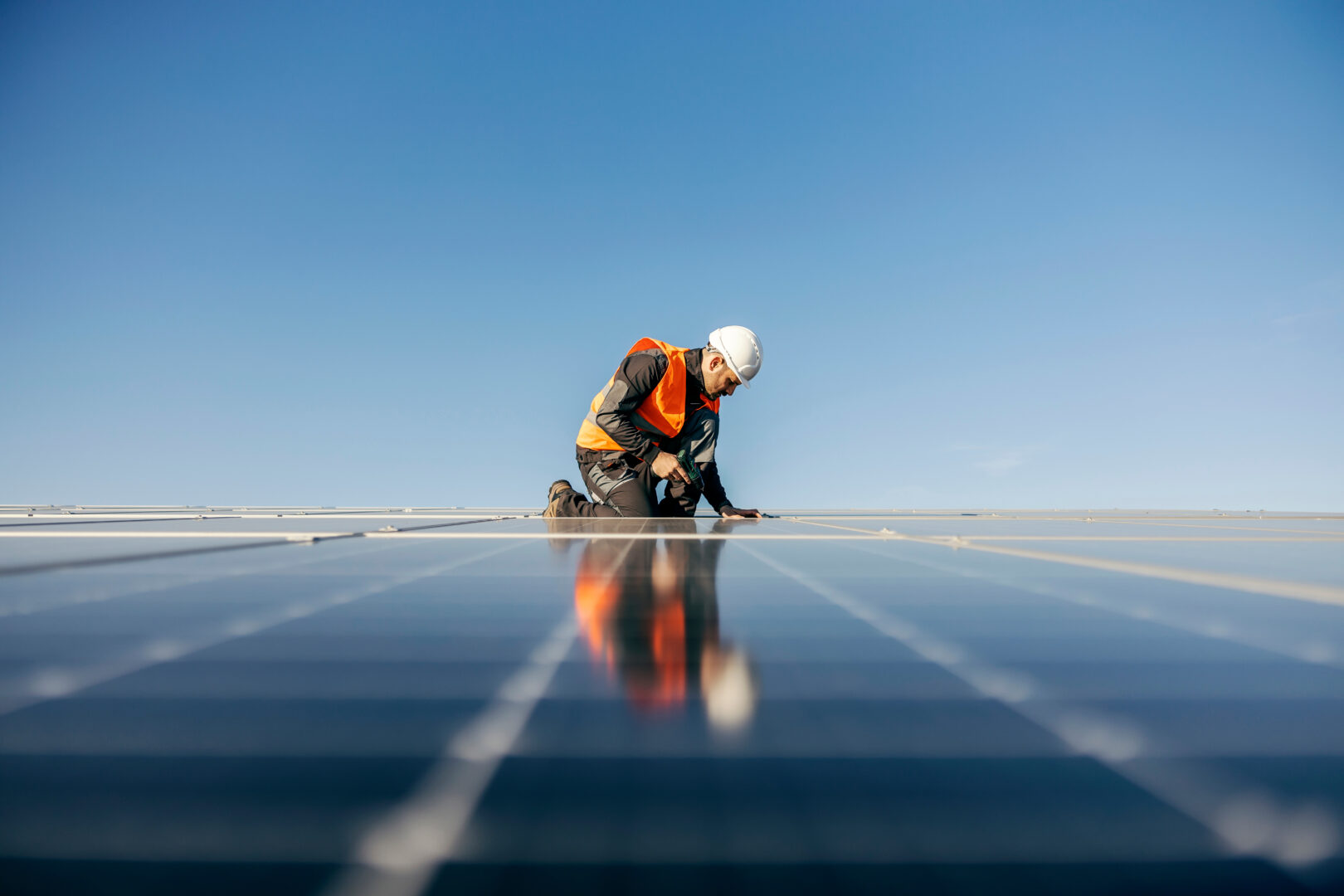 Worker kneeling and sets solar panel